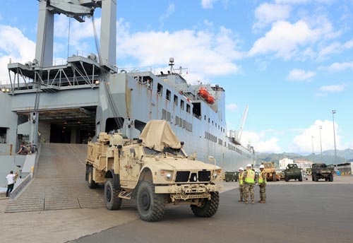 Photograph of military vehicles being unloaded from a transport vessel.